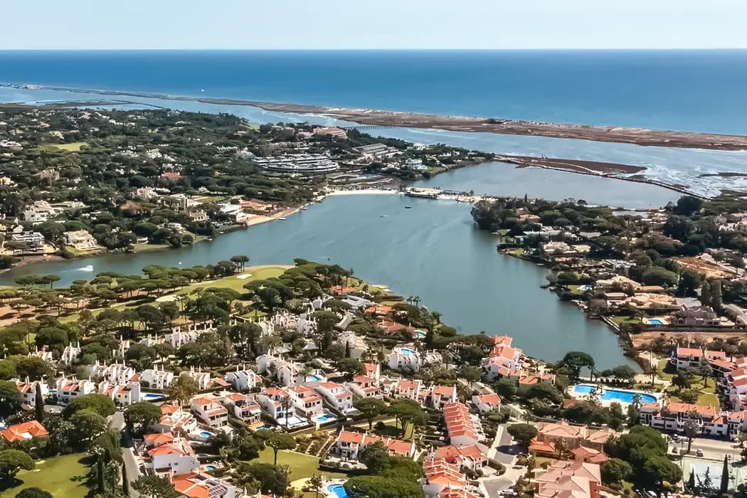 Aerial view of the Algarve's Ria Formosa with lagoons, greenery and red-roofed homes by the Atlantic Ocean