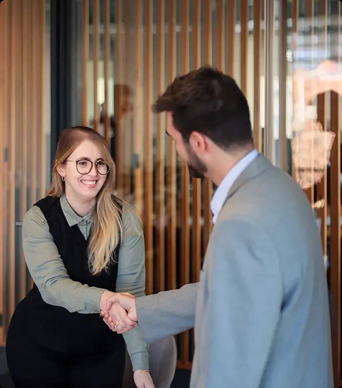 young woman and a man exchanging a handshake in a meeting room