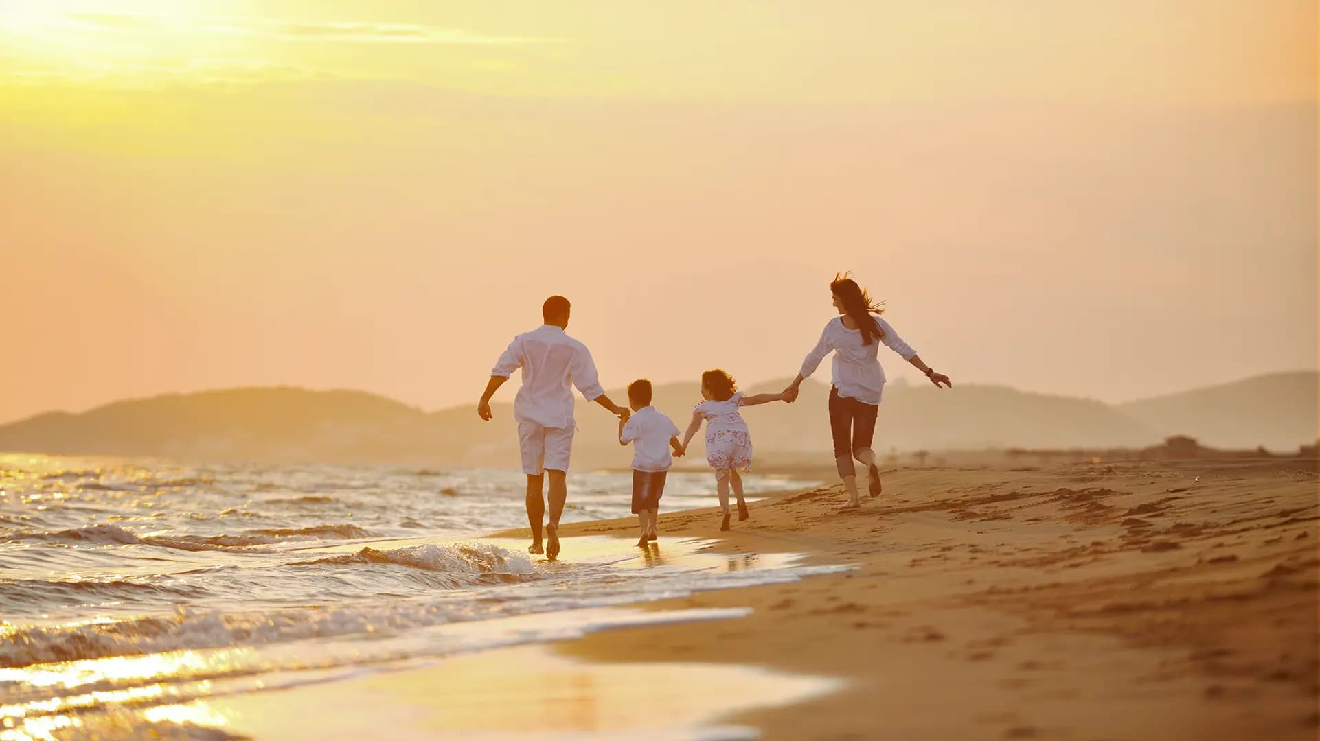 A family walking along a beach with golden light and sand