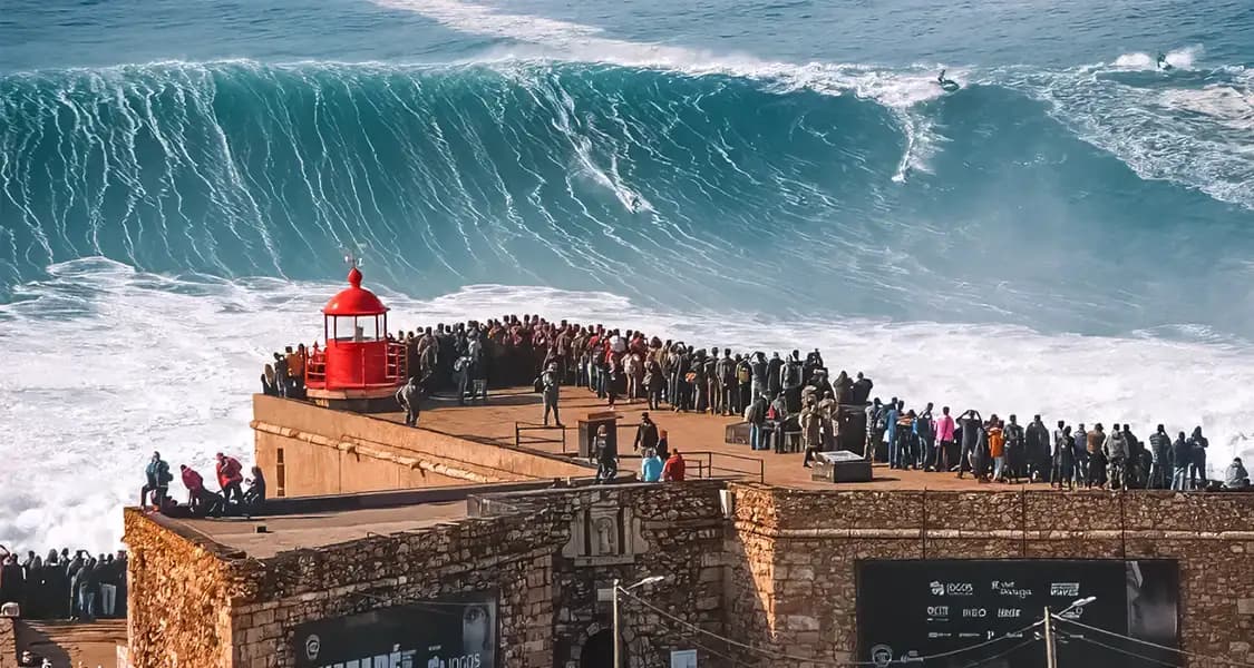 Giant wave in Nazaré, Portugal, with a crowd gathered by the lighthouse