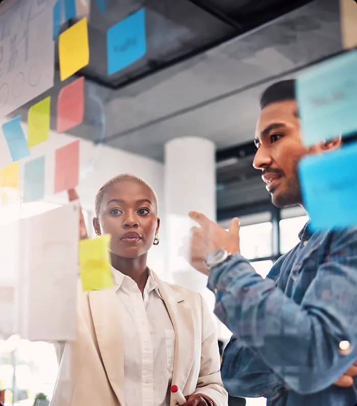 a couple of entrepeneurs discussing a project in front of a brainstorming board