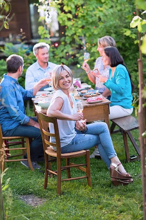 riends enjoying a garden dinner and raising glasses around a wooden table